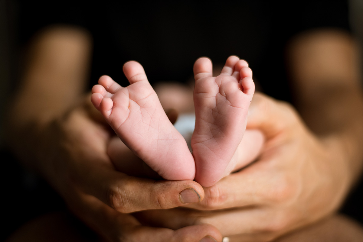 Parents hold an infant so you can see the baby's feet