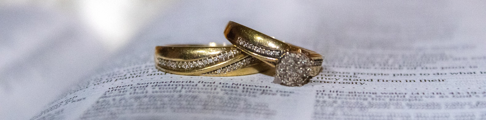 Two wedding rings laying on top of an opened Bible